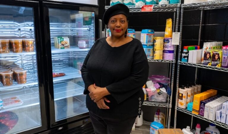 A woman standing in a pantry with food on shelves smiling.