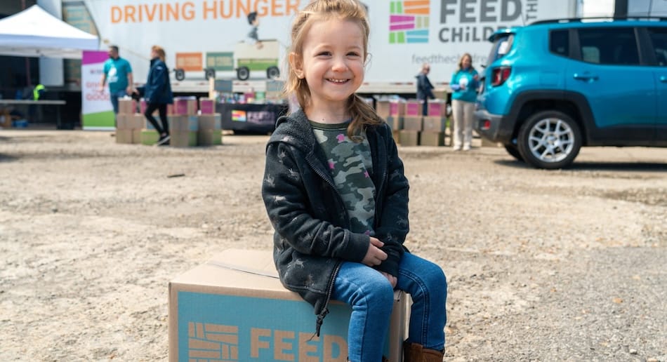 Un niño sentado en una caja sonríe en un evento al aire libre