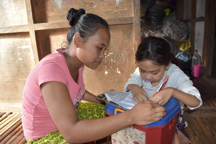 Una madre y su hija escribiendo en un papel