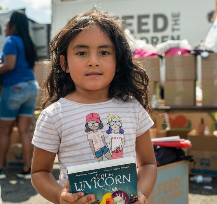 Una chica con un libro en la mano en un evento al aire libre