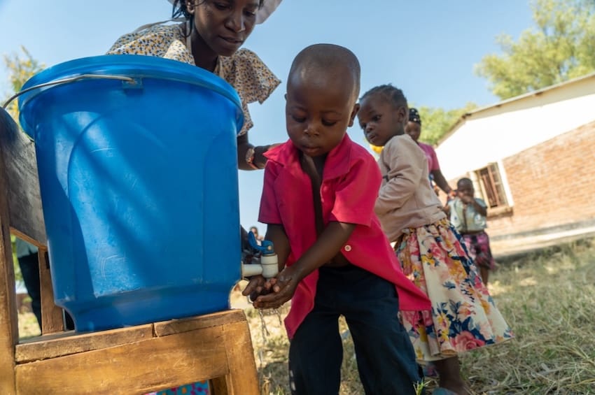 Un grupo de niños con un cubo de agua al aire libre